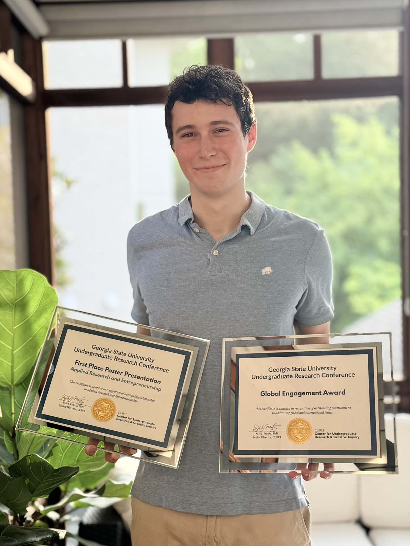 Drew Thomasson holding his two Georgia State Undergraduate Research Conference awards